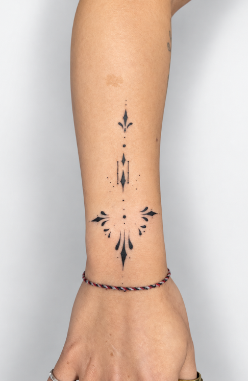 Tatuaje fine line minimalista con símbolos ornamentales y geométricos realizado por Ink Brothers Tattoo Studio en Cusco